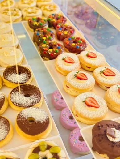 Vitrine da Doce Donuts com donuts tradicionais de chocolate, confete colorido e cobertura rosa